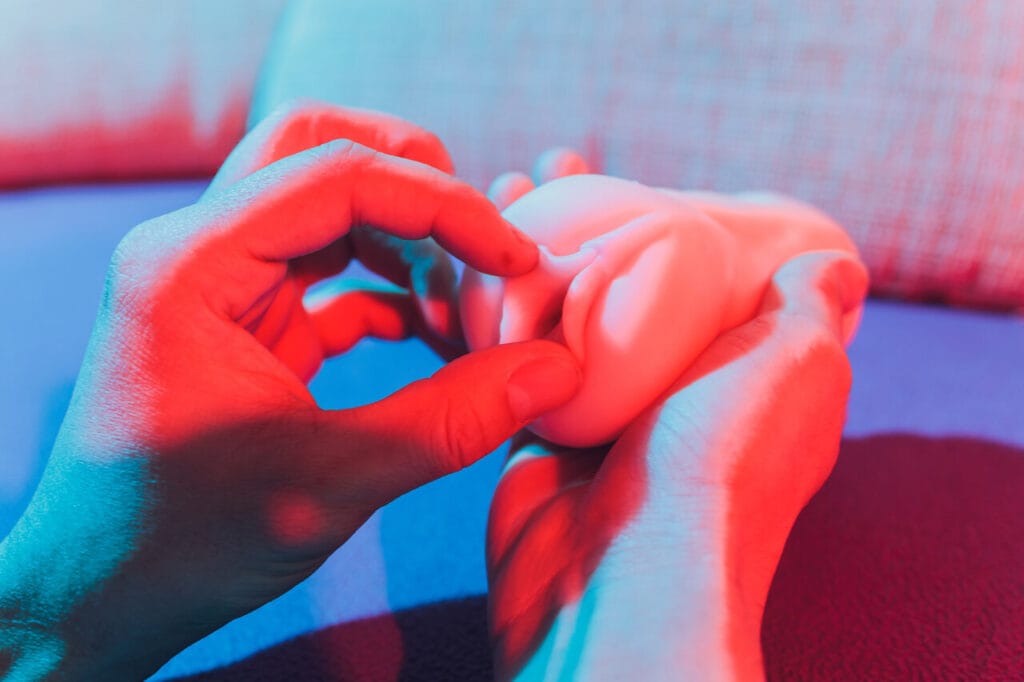 Kädet pitelevät realistista tekovaginaa värikkäässä valaistuksessa – suositun masturbaattorin yksityiskohtainen lähikuva